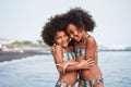 Black sister twins having fun on the beach during summertime - Little female kids laughing and hugging each others - Love and