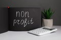 Black sketchbook with phrase Non Profit, calculator and houseplant on white table Royalty Free Stock Photo