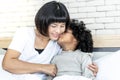 black skin African girl kissing her mother`s cheek with love on white bed Royalty Free Stock Photo