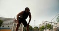 A Black-skinned athlete in a black sports summer uniform finishes his run, exhales and descends into the room under the