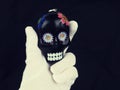 Black skull in hand in white glove, symbol of Halloween, day of veneration of the dead