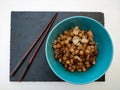 Black slate base with blue bowl of chickpeas with tofu and onion with chopsticks on white background Royalty Free Stock Photo