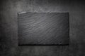 Black slate board on dark stone texture top view. Empty space for menu or recipe