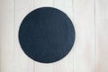 Black slate round stand for cheese or snacks on a white wooden table Royalty Free Stock Photo