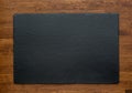 Black slate stone on wooden background, top view Royalty Free Stock Photo