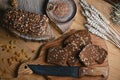 Black sliced bread on the board, vintage knife, wheat shoots, flax seed, on the table and a wooden background on a stump, concept Royalty Free Stock Photo