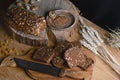 Black sliced bread on the board, vintage knife, wheat shoots, flax seed, on the table and a wooden background on a stump, concept Royalty Free Stock Photo