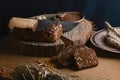 Black sliced bread on the board, vintage knife, wheat shoots, flax seed, than slicing bread on the table and a wooden background o Royalty Free Stock Photo