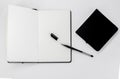 Black small closed square notepad and large open notebook with blank white pages and ballpoint pen with cap on white back Royalty Free Stock Photo