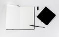 Black small closed square notepad and large open notebook with blank white pages and gel pen Royalty Free Stock Photo