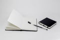 Black small closed square notepad and large open notebook with blank white pages and gel pen with cap. Empty paper. Office Royalty Free Stock Photo