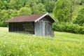 Black small wooden house in the field with forest in the background Royalty Free Stock Photo