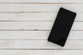 Black smartphone with dark screen on white wood texture background Royalty Free Stock Photo