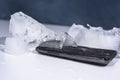 Black smartphone frozen in ice. Abstract object photo