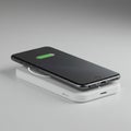 A black smartphone rests on a rectangular white wireless charging pad. The phone Royalty Free Stock Photo