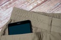 Black smartphone sticking out of pocket light pants Royalty Free Stock Photo