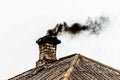 Black smoke from the chimney of an apartment building during heating and heating on the roof of slate Royalty Free Stock Photo