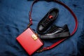 Black sneakers with red tongues and a red bag with a golden lock on a blue woven background