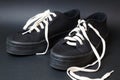 Black sneakers with white untied laces on a black background Royalty Free Stock Photo