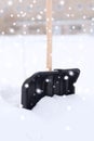 Black snowshowel with wooden handle in snow pile