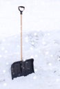 Black snowshowel with wooden handle in snow pile