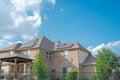 Black solar panels on shingle roofing of two story suburban residential house under sunny cloud blue sky in Flower Mound, Texas,