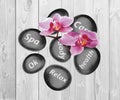Black spa stones and orchid flowers on wooden background Royalty Free Stock Photo