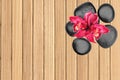 Black spa stones and pink orchid flower on wooden Royalty Free Stock Photo
