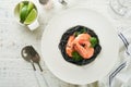 Black spaghetti pasta shrimp on black plate on wooden white table background. Squid ink pasta with prawns. Pasta seafood. Top view Royalty Free Stock Photo