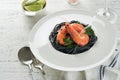 Black spaghetti pasta shrimp on black plate on wooden white table background. Squid ink pasta with prawns. Pasta seafood. Top view Royalty Free Stock Photo
