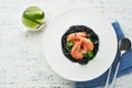 Black spaghetti pasta shrimp on black plate on wooden white table background. Squid ink pasta with prawns. Pasta seafood. Top view Royalty Free Stock Photo