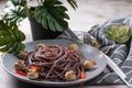 black spaghetti with red pepper on a plate.