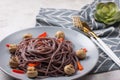 black spaghetti with red pepper on a plate.