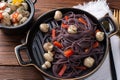 black spaghetti with red pepper on a plate.