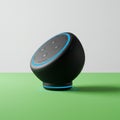 A black, spherical smart speaker with a textured surface is positioned on a flat, green Royalty Free Stock Photo