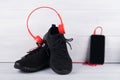 On black sport shoes are wearing red headphones for music next to a mobile phone on a light background Royalty Free Stock Photo