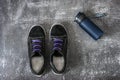 Black sports sneakers with two-tone laces along with a blue plastic container with water on a gray surface Royalty Free Stock Photo