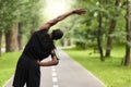 Black sportsman exercising before jogging, back view