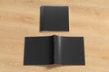 Black square brochure or booklet cover mock up on wooden background. Closed one brochure and upside down other. Royalty Free Stock Photo