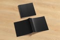 Black square brochure or booklet cover mock up on wooden background. Closed one brochure and upside down other. Clipping path arou Royalty Free Stock Photo