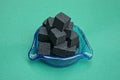 black square charcoal for a hookah in a blue glass ashtray Royalty Free Stock Photo