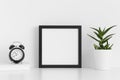 Black square frame mockup with a aloe vera in a pot and workspace accessories on a white table Royalty Free Stock Photo