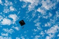 A black square kite soaring through the sky on a sunny day, A mortarboard tossed high in the air against a vibrant blue sky Royalty Free Stock Photo