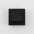 Black square light switch with a modern design on a white wall. The switch has a flat, Royalty Free Stock Photo