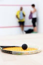 Black squash ball on rackat close up foreground focus.