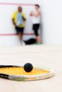 Black squash ball on rackat close up foreground focus.