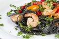 Black squid ink Fettuccine pasta with prawns or shrimps cherry tomatoes, parsley, chili in wine and butter sauce Royalty Free Stock Photo