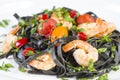 Black squid ink Fettuccine pasta with prawns or shrimps cherry tomatoes, parsley, chili in wine and butter sauce Royalty Free Stock Photo