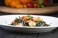 Black squid ink Fettuccine pasta with prawns or shrimps cherry tomatoes, parsley, chili in wine and butter sauce Royalty Free Stock Photo