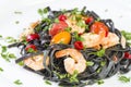 Black squid ink Fettuccine pasta with prawns or shrimps cherry tomatoes, parsley, chili in wine and butter sauce Royalty Free Stock Photo